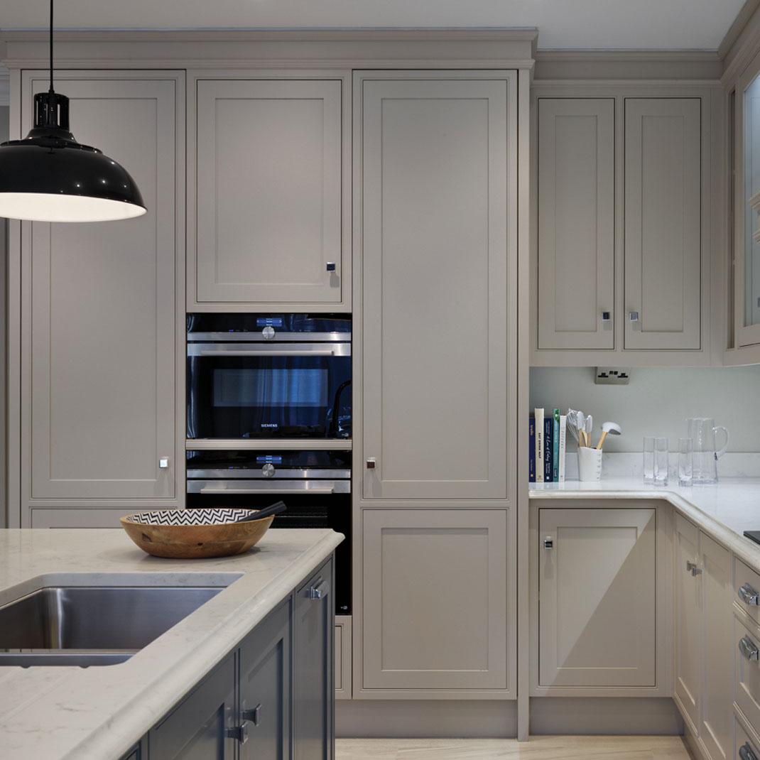 Muted Grey Classic Inframe Kitchen Muted grey classic in-frame kitchen by Charles Yorke, showcasing a built-in double oven housing and a marble island with a sink.